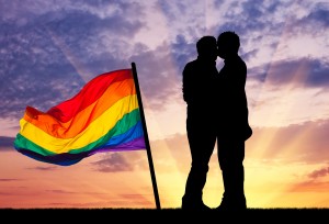 Concept of gay people. Silhouette happy gay kissing against the evening sky and a rainbow flag
