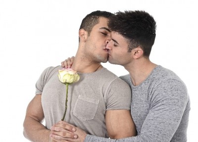 two men kissing holding a flower