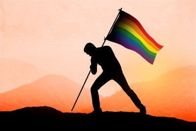 silhouette of man raising pride flag