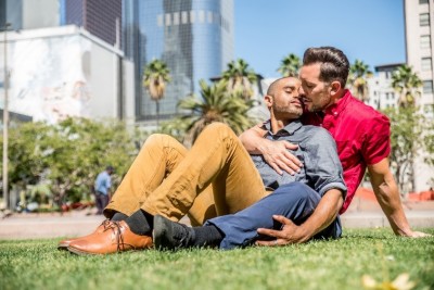two men kissing on a park bench