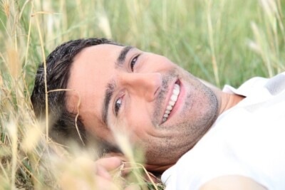 man smiling in grassy field