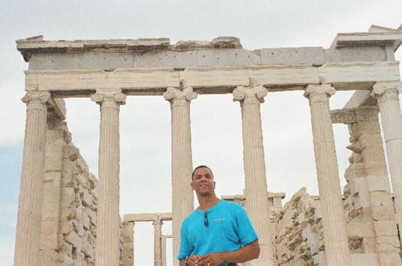a man standing in front of an ancient Greek building